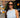 A woman wearing a sleeveless, light blue and white vertically striped ribbed mini dress and dark sunglasses, walking on a city street.