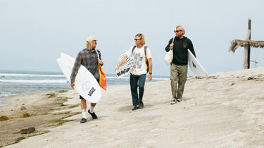 Brothers heading to a surf sesh on the beach with their sunglasses and boards