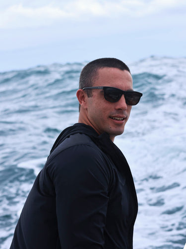 Man wearing sunglasses with ocean waves in the background
