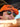 Person wearing an orange cap with a logo and sunglasses, outdoors.