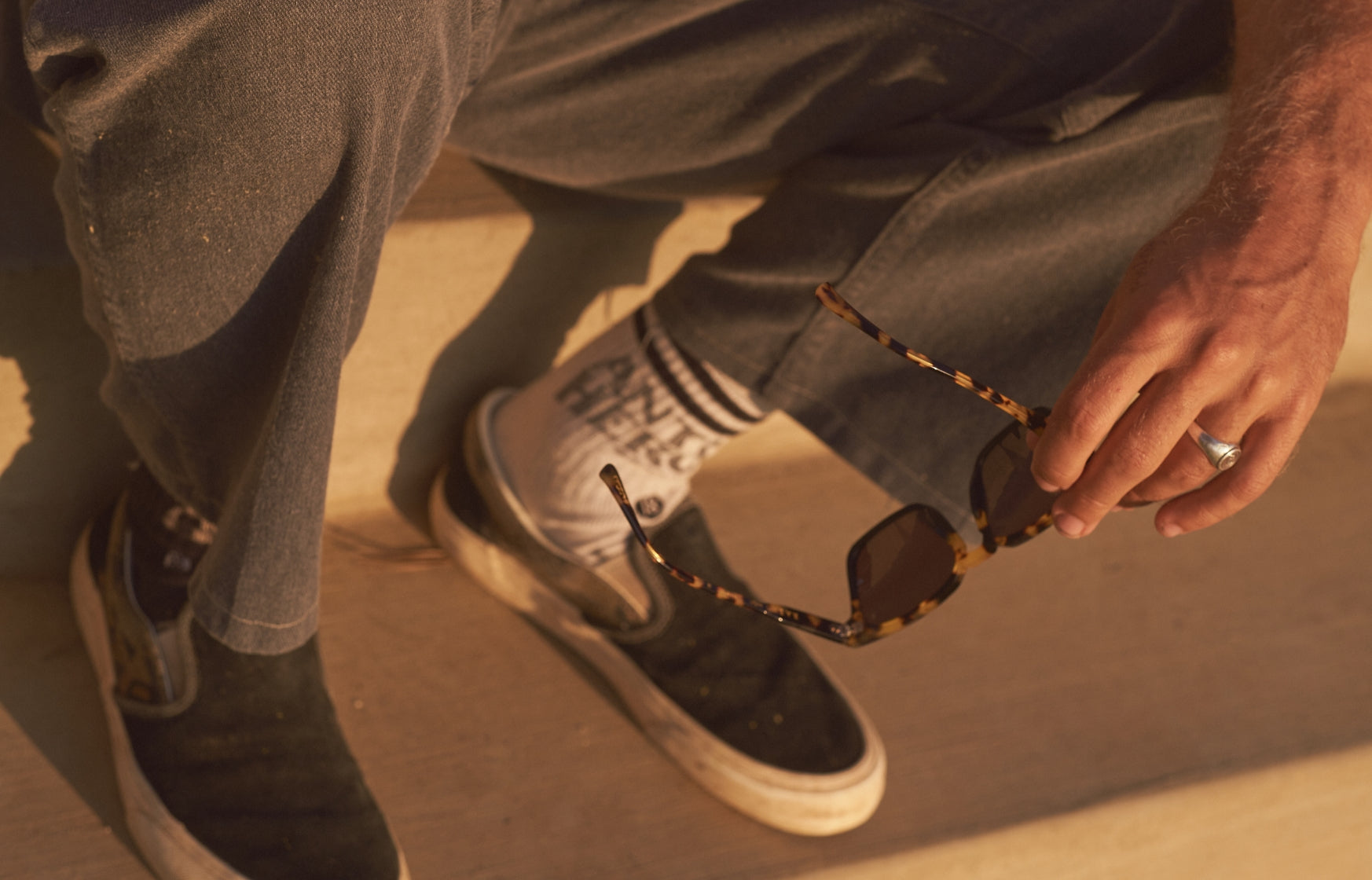 Man holding sunglasses with ring and skate shoes