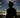 Silhouette of a person on a beach with ocean waves and sky.