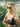 Woman wearing a black sports bra and sunglasses outdoors with greenery in the background