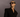 Woman wearing a black blazer and sunglasses against a dark background