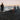 Three people around a campfire on a beach at sunset.