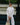 Woman in a white outfit holding a straw bag with a blurred background